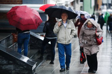 Nisan 2015 - Vladivostok, Rusya - Şehirde yağmur. Yağmur sırasında şemsiye altındaki insanlar ıslak sokaklarda gezerler..