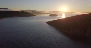 Yukarıdan ateş ediyorlar. Şafak vakti Primorsky Bölgesi 'nin Lazovsky Reserve' indeki Petrov adasının üzerinde uçacağız. Güneş ufuktan yükselir denizin ve adanın arka planına karşı.