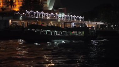 Chao Phraya Nehri. Parlak dükkanların, alışveriş merkezlerinin ve restoranların ortasında gece vakti bir teknede yelken açmak..