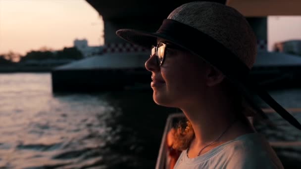 享受快乐 黄昏时分 美丽的姑娘从船舷看去 就在河边和日落的背景上 — 图库视频影像
