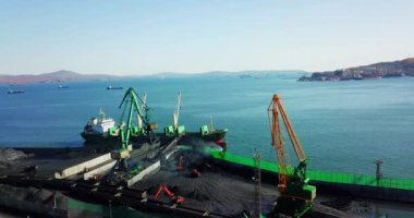 İlkbahar, 2019 Nakhodka, Primorsky Bölgesi. Kömür portu. Nakhodka 'nın küçük bir kasabasındaki bir kömür limanında uçuyor. Kömür, deniz kömür limanındaki bir kargo gemisine yükleniyor..