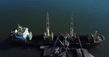 İlkbahar, 2019 Nakhodka, Primorsky Bölgesi. Kömür portu. Nakhodka 'nın küçük bir kasabasındaki bir kömür limanında uçuyor. Kömür, deniz kömür limanındaki bir kargo gemisine yükleniyor..