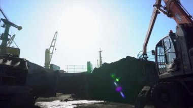 2018 Yazı Nakhodka, Primorsky Bölgesi Kömür Limanı. Kazı makinesi bir kova yardımıyla kazıdan konveyör bandına kömür taşır. Bir kargo gemisine siyah kömür yüklemek.