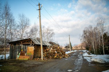 Rus köyü. Ahşap evlerin ve çitlerin arkasındaki bir Rus köyünün ortasındaki kötü toprak yol. Baharda çamurlu kırsal yolda su birikintilerinde.