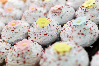 Yakın plan. Beyaz kremalı paskalya pastaları tezgahın üzerinde sıralanmış duruyor. Paskalya çörekleri.