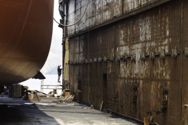 Tersane. Tersanenin kuru rıhtımında bir gemi duruyor..