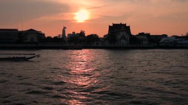 Ağır çekimde çekim. Chao Phrai Nehri, Bangkok 'ta. Turist uzun botu batan güneşe karşı nehirde yüzer..