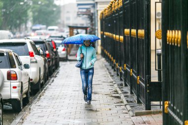 2015 yazında Vladivostok, Rusya 'da yağmurlu bir hava vardı. İnsanlar şehrin ıslak sokaklarında hafif yağmurda şemsiye altında yürürler..