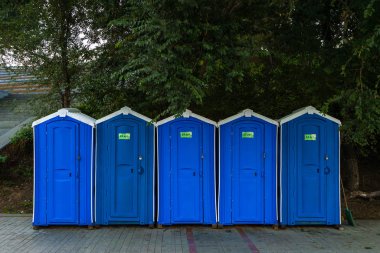 Yeşil ağaçların arka planında mavisiyle bir sıra kuru sokak dolabı.