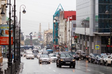 2015 yazında - Vladivostok, Rusya - Vladivostok sokakları yağmurdan ıslandı. Yağmur sırasında, su birikintileri arasında arabalar şehrin merkezinden geçer..