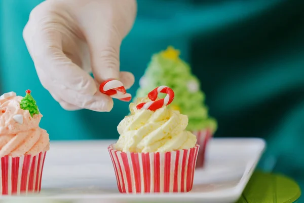 New Year\'s treats. A pastry chef decorates Christmas cakes with rubber gloves.