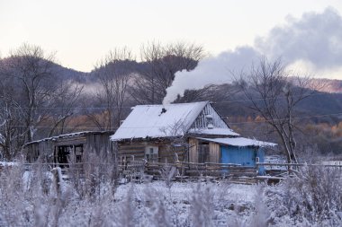 Primorsky Bölgesi 'nde Rusya' ya dönen Latin Amerikalı eski inananların köyü. Eski inananların ahşap evleri güzel tarlalar ve dağların arka planında kar yağışı sırasında.