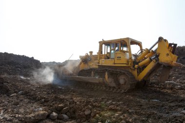 2015 sonbaharında - Primorsky bölgesi, Rusya - Sanayi fotoğrafçılığı. Sarı kazıcı bir kum ocağında çalışıyor. Ağır bir kazıcı büyük bir kazıda bir tseben tırmıklıyor.