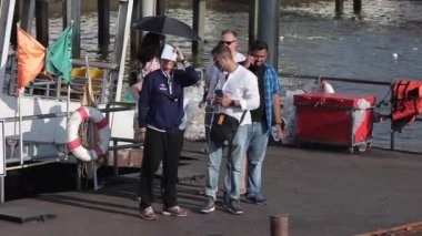 2019 baharında Bangkok, Tayland 'da Chao Phraya Nehri' nde tekne gezisi. Ağır çekim. Turist teknesi rıhtımın yanından geçiyor ve turistler tekneyi bekliyor.