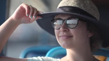 Bangkok 'taki Chao Phraya Nehri' nde tekne gezisi. Ağır çekim. Nöro-Avrupalı yüzü olan güzel bir kız görüş için gözlük takıyor ve bir şapka turist teknesinin manzarasının keyfini çıkarıyor.