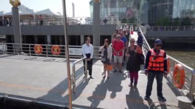 2019 baharında, Bangkok, Tayland 'da Yavaş Hareket. Turistler Chhao Praia Nehri 'ndeki ağlayan nehir rıhtımında bir zevk teknesinin demirlemesini bekliyorlar.