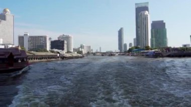 2019 baharında, Bangkok, Tayland 'da Yavaş Hareket. Bir turist teknesinin yanından Chhao Praia Nehri manzarası. Bangkok 'un ana nehrinin arka planındaki uzun ve güzel binalar.