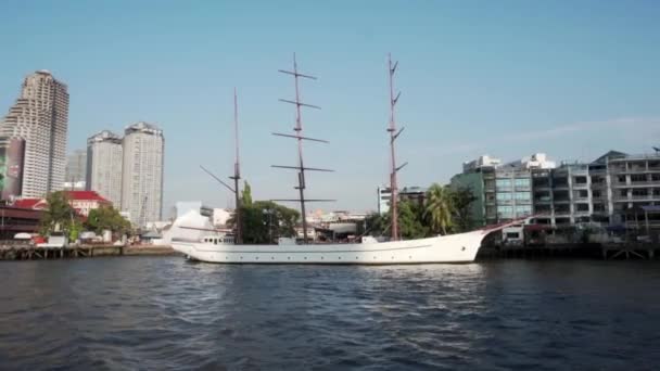 2019年夏 バンコク チャオプラヤ川沿いの観光船に乗って歩く 川の駅に係留された美しい白い帆船の前を泳ぐ喜びのボート — ストック動画
