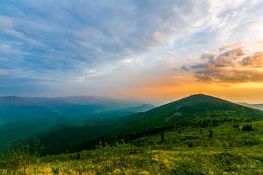 Güzel manzara. Yazın dağın tepesinden parlak renkli günbatımı açılıyor. Gün batımında fırtına bulutları. Rahatla.