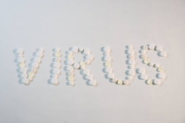 Coronavirus Covid - 19. Virüs kelimesi beyaz arka planda çeşitli yuvarlak tıbbi haplarla yayılmış..