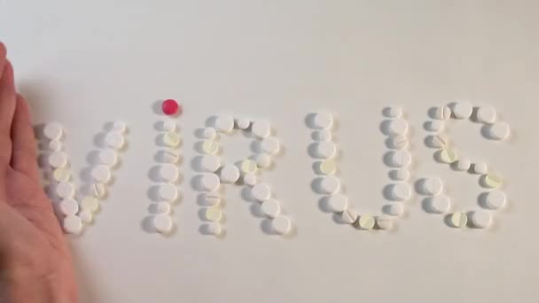 Covid-19. La main masculine fouette le mot Virus, disposé dans différentes pilules médicales, sur un fond blanc .