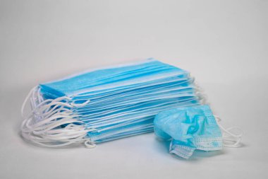 Tıbbi steril tek kullanımlık maskeler. Buruşuk tıbbi maske beyaz bir arka plandaki yeni maske yığınının arka planında yatıyor.
