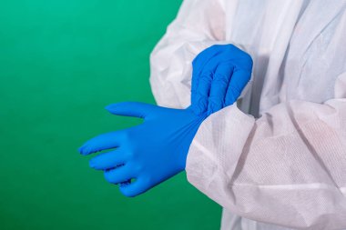 COVID-19. Yığının üzerinde yüz maskeleri var. Salgın geçmişi. Kadın doktorların ellerini kapat. Ofiste mavi sterilize cerrahi eldiven giy..