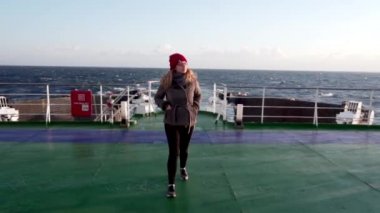 2019 ilkbaharında - Japonya Denizi, Rusya - Doğu Rüyası yolcu feribotu. Japon Denizi 'ndeki bir gemi gezisi sırasında kırmızı şapkalı genç bir kız feribotun üst güvertesinde yürüyor. Yolcu feribotu gün batımına hayran..