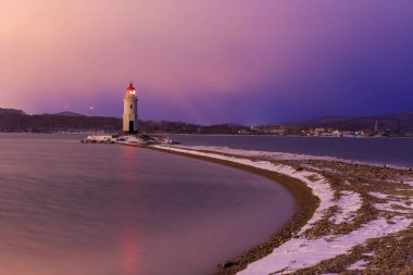 Deniz kenti Vladivostok 'ta şafak vakti. Tokarevsky deniz feneri rengarenk bir şafakta güzel bir denizin arka planına karşı.