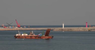 Güney Kore 'nin Donhe limanındaki bir körfezde eski paslı bir mavna yüzüyor.