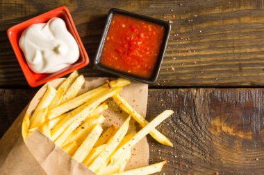 Taze patates kızartması salsa ve ahşap zemin üzerine mayonez ile kızarmış. Dokulu bir arka plan. Kopyala Yapıştır yer