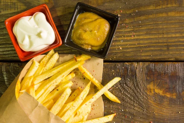 Taze patates kızartması hardal ve mayonez ahşap arka plan üzerinde kızarmış. Dokulu bir arka plan. Kopyala Yapıştır yer