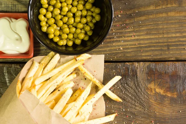 Taze patates kızartması mayonez ve bezelye ahşap arka plan üzerinde kızarmış. Dokulu bir arka plan. Kopyala Yapıştır yer