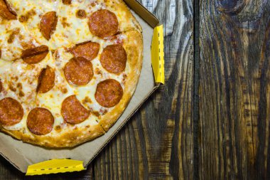 Ahşap masa üzerinde üzerinde karton kutu İtalyan pizza. Dokulu bir arka plan. Kopyala Yapıştır yer.