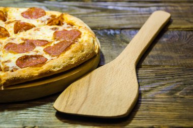 Salam koyu ahşap zemin üzerine İtalyan biberli pizza. Geleneksel İtalyan yemekleri. Dokulu bir arka plan. Kopyala Yapıştır yer