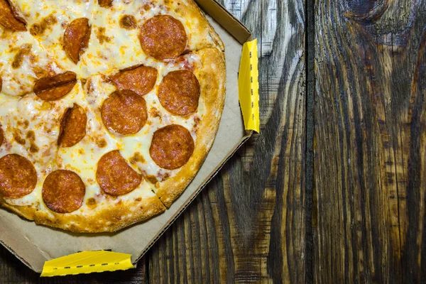 Ahşap masa üzerinde üzerinde karton kutu İtalyan pizza. Dokulu bir arka plan. Kopyala Yapıştır yer.