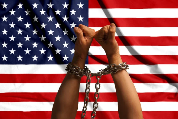 Dwie ręce spętany łańcuszka na tle flagi Usa — Zdjęcie stockowe