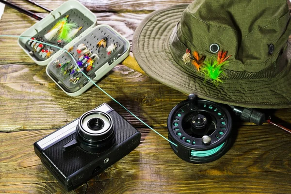 Spinning, fly fishing, flies, spinners, hat, camera for photographing the trophies and frame for your label lying on a wooden table.