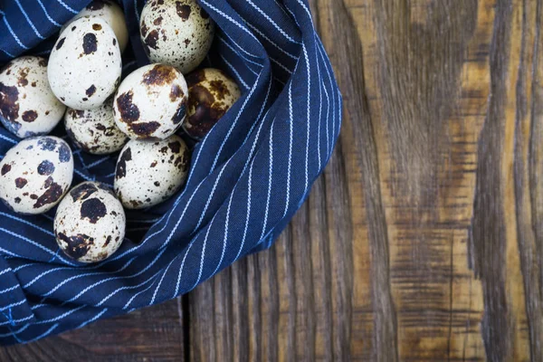 Uova di quaglia su un tovagliolo a forma di nido su uno sfondo di legno rustico — Foto Stock