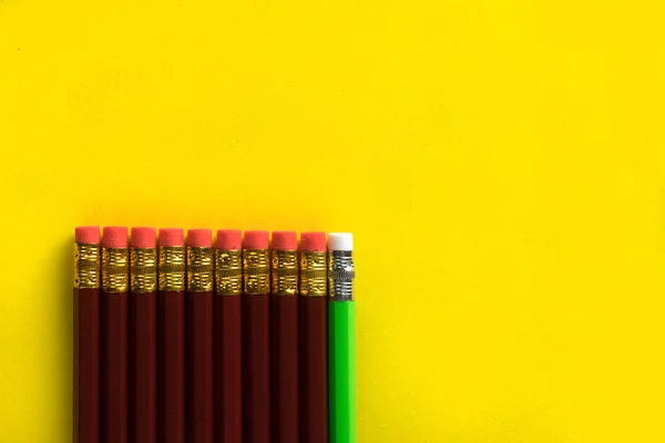 Бизнес-концепция - много одинаковых карандашей и один другой карандаш на фоне желтой бумаги. Это символ лидерства, командной работы . — стоковое фото