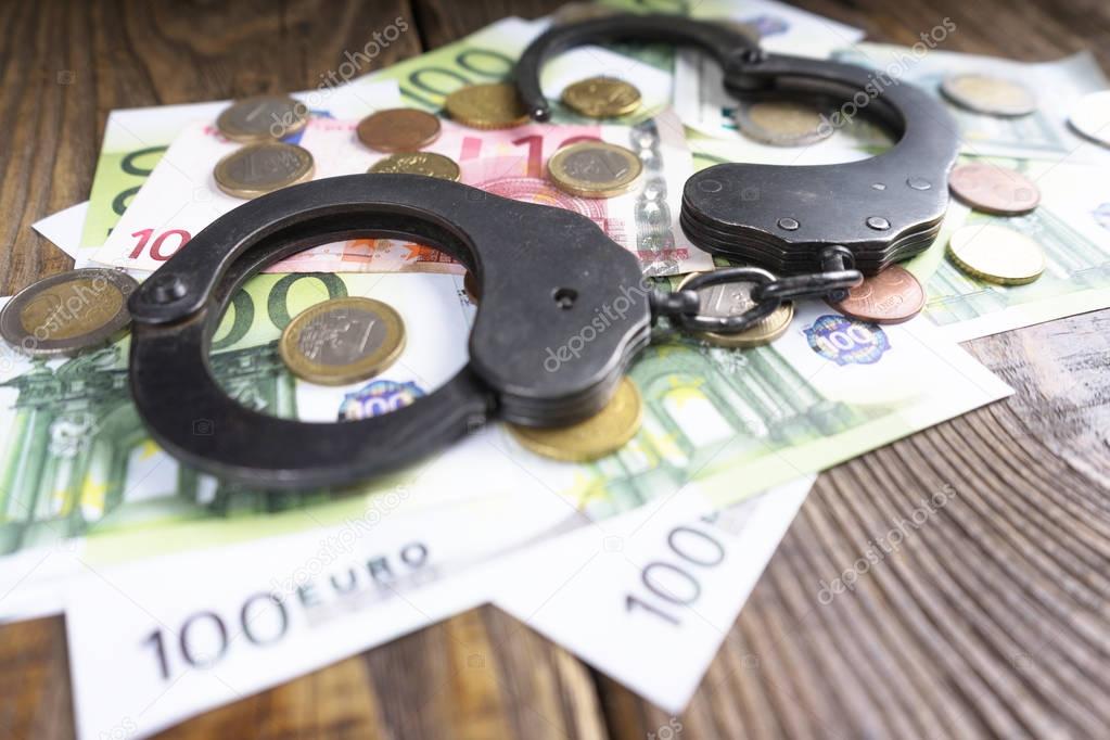 Handcuffs on a pile of euro banknotes. The symbolic meaning of economic crimes.
