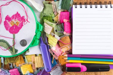 İşlemeli kırmızı çiçek, çemberler, konu, kalem, marker ve Not Defteri ile tuval üzerine ahşap masa