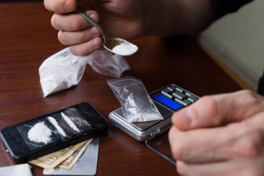 Uyuşturucu satıcısı paketleri üzerinde ölçekler ağırlığında ilaçların.