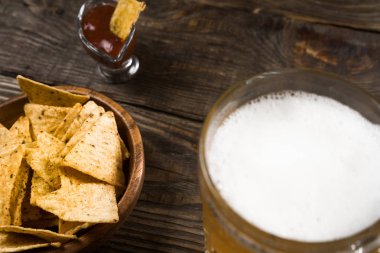 Bir ahşap masa bir fincan filtre uygulanmamış bira, cips ve salsa. Kopyala Yapıştır