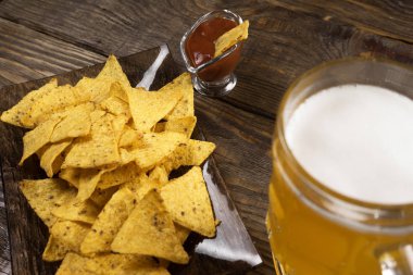 Bir ahşap masa bir fincan filtre uygulanmamış bira, cips ve salsa. Kopyala Yapıştır