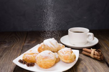 Lezzetli eklerleri şeker, krema ile serpilir üzerinde ahşap bir masa standı. Kopya spase.