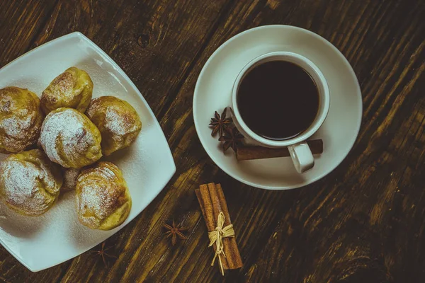 Eclairs pyszne posypane pudrem cukrem, stanąć na drewnianym stole. Skopiuj spase. — Zdjęcie stockowe