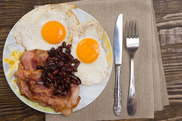 Deska s míchanými vejci, slaninou a fazole na dřevěný rustikální stůl. — Stock fotografie