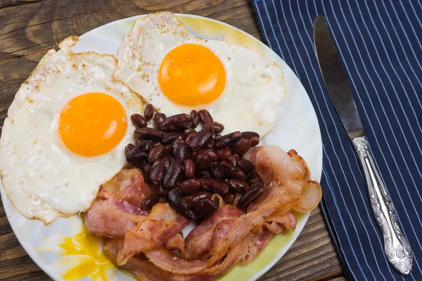 Πιάτο με αυγά ομελέτα, μπέικον και τα φασόλια σε ένα ξύλινο τραπέζι ρουστίκ. — Φωτογραφία Αρχείου