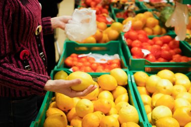Kadın bir süpermarkette limon seçer. Kopya alanı.